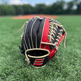 A close-up image of a red and black baseball glove resting on a grassy field. The glove is positioned with the palm facing upward, showcasing its intricate blonde lacing and padded leather design. In the background, there is a blurred view of a baseball diamond, indicating that the setting is likely a sports field. The focus on the glove against the soft-focus backdrop highlights its details and suggests its readiness for use in a game.